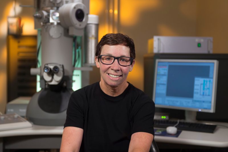 Deb Kelly sits in front of an electron microscope. 